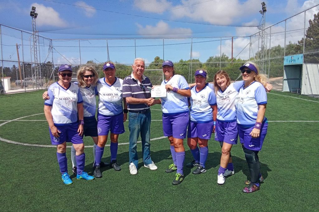Photograph of ladie's football team handing over cheque to charity chairman