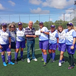 Photograph of ladie's football team handing over cheque to charity chairman