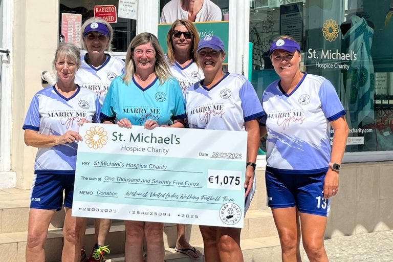 Photograph of ladie's football team holding large cheque of fundraised money